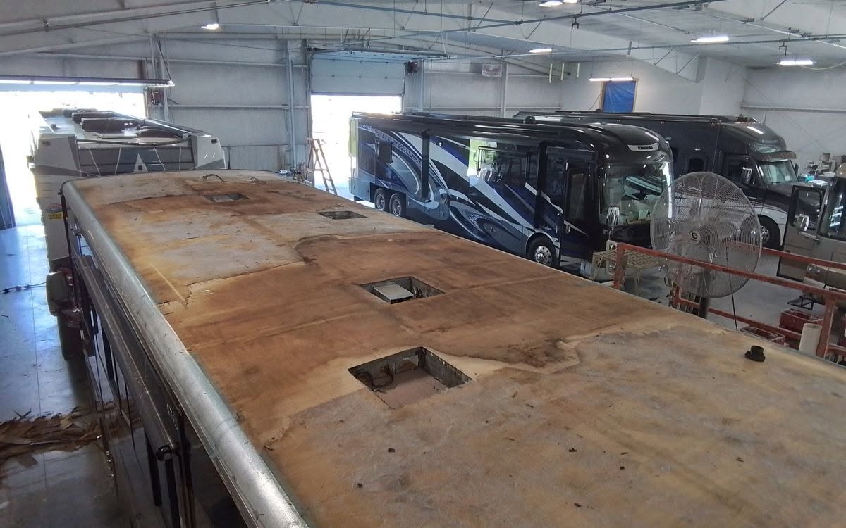 Exposed coach roof during replacement work inside a repair workshop