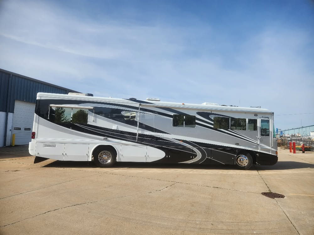 Silver and black motorcoach outside a workshop